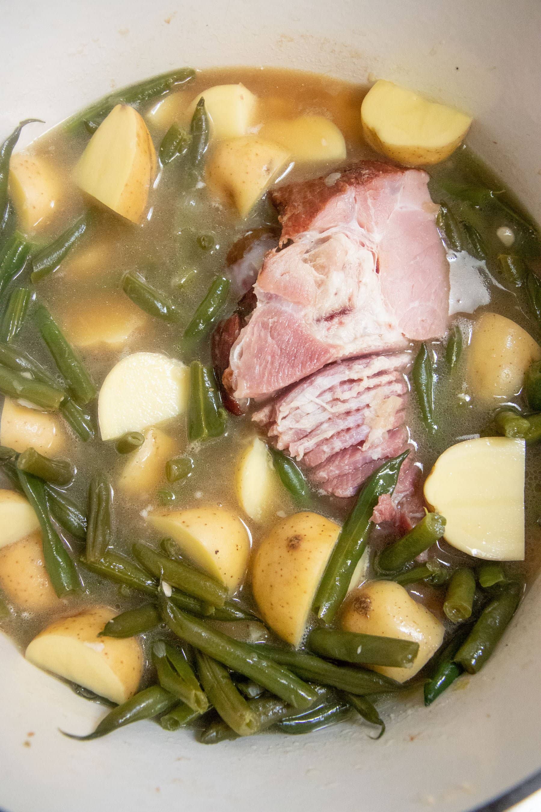 Ham simmering in a pot of beans and new potatoes