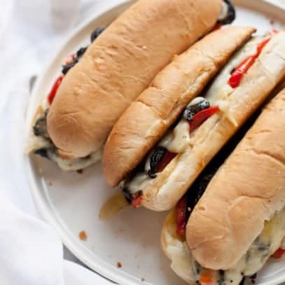 Overhead close-up shot of three portabella cheesesteaks on a white plate