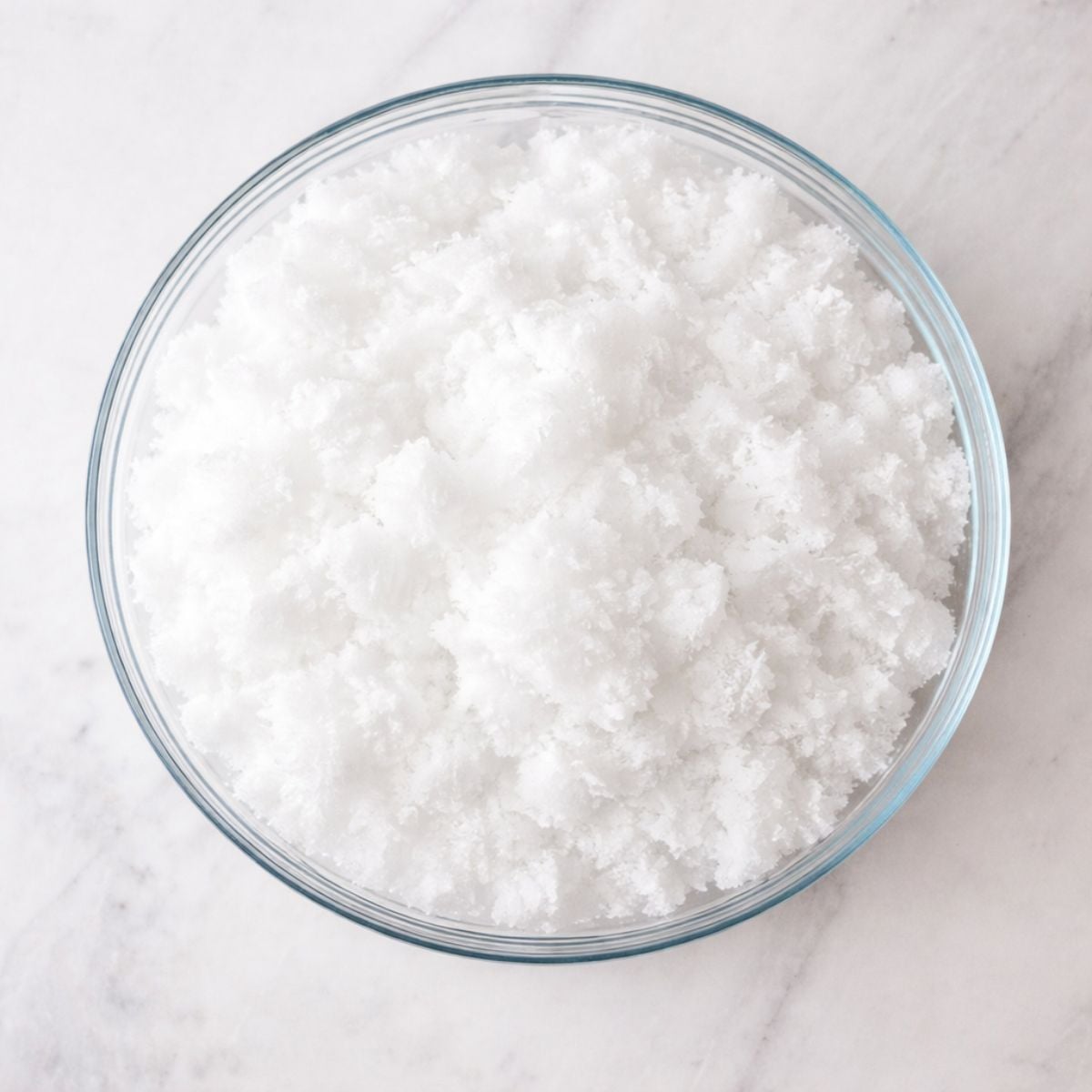 A glass bowl of fresh snow on a countertop