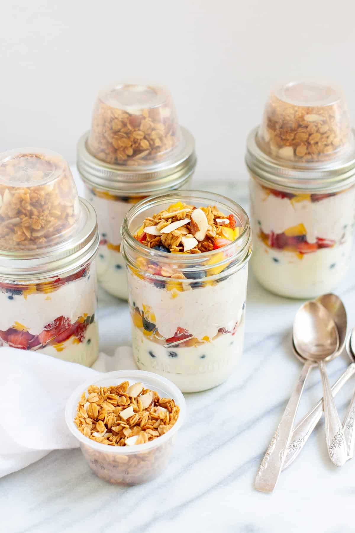 Side angle shot of prepared Meal Prep Fruit and Yogurt Parfaits in glass jars