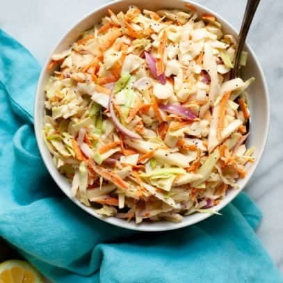 Overhead shot of Sweet and Creamy Coleslaw in a white bowl on top of a blue towel