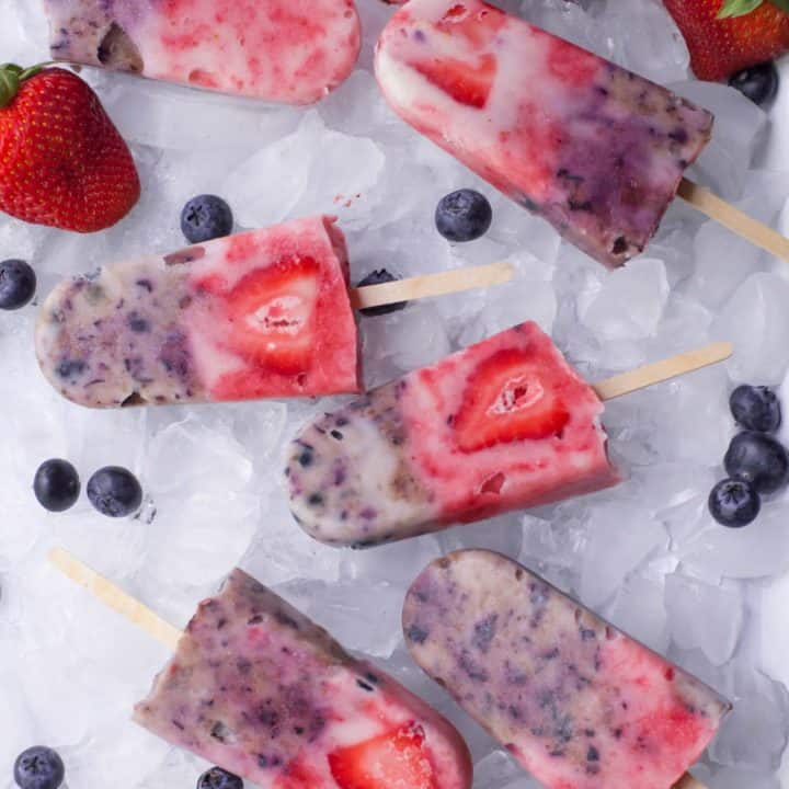 Six berry popsicles lay on a bed of ice
