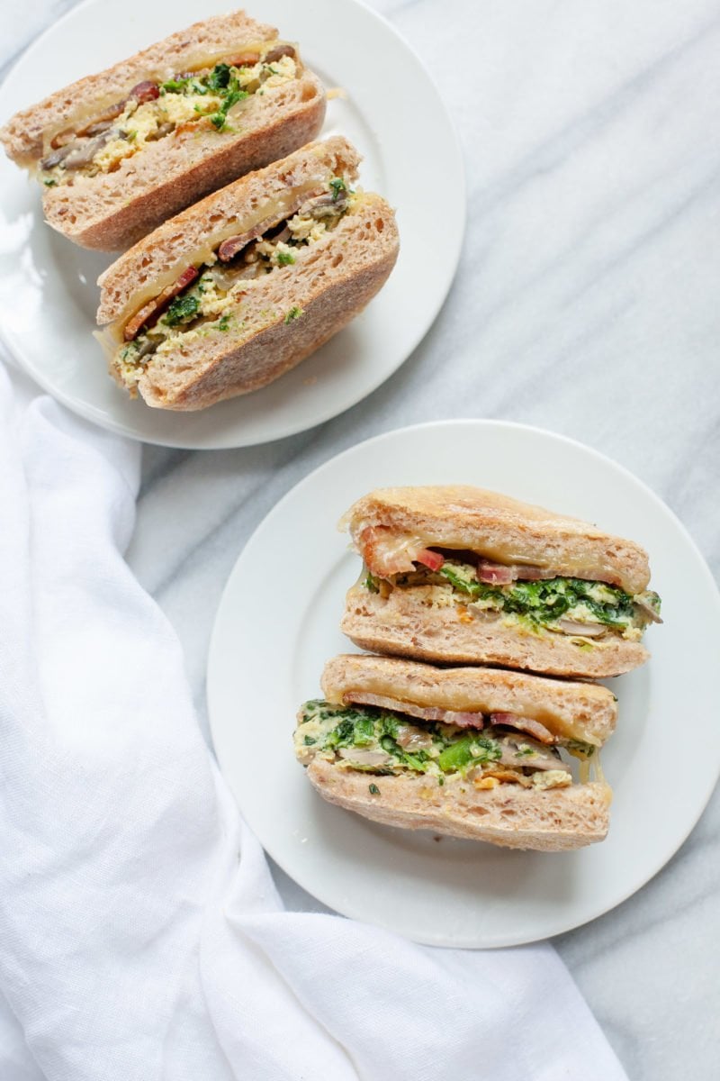 Overhead shot of two Meal Prep Breakfast Sandwiches, each cut in half and on a white plate