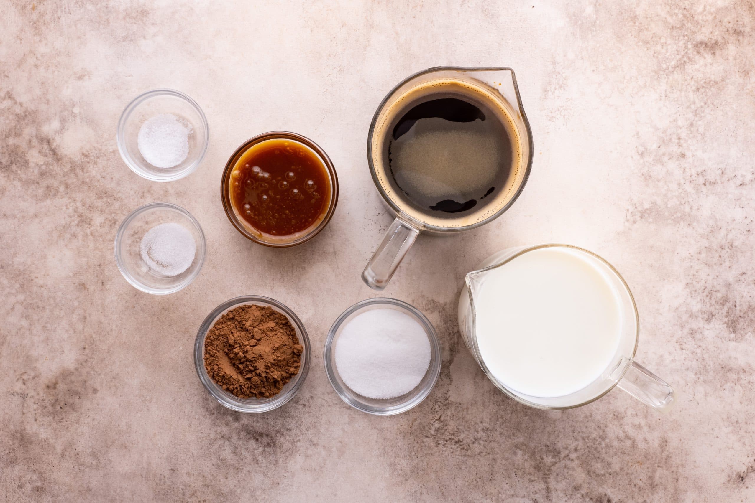 Overhead shot of small bowls and liquid measuring cups holding mocha ingredients