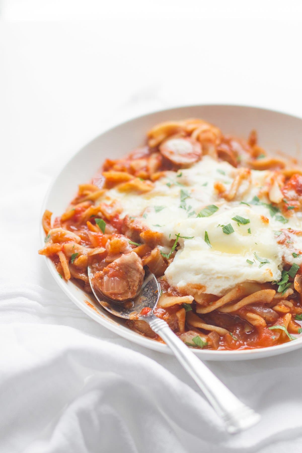 A spoon sits in a bowl of slow cooker lasagna soup.