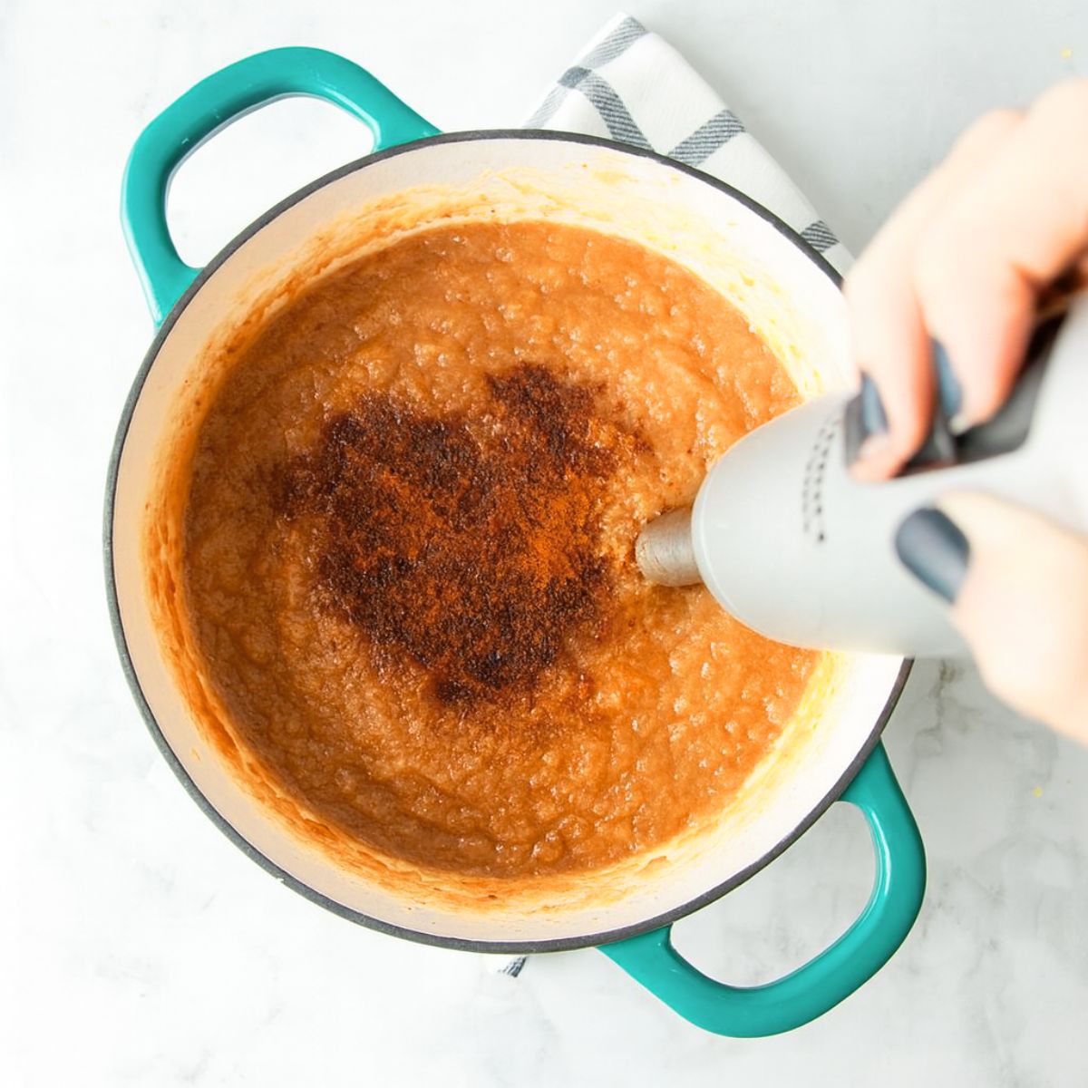 Blending cinnamon into applesauce using an immersion blender