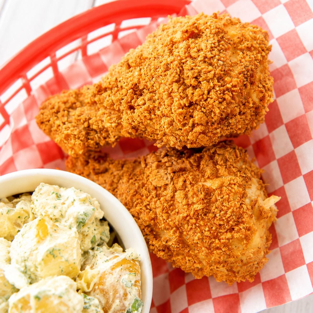Close-up of crispy cornflake-crusted chicken drumsticks and potato salad