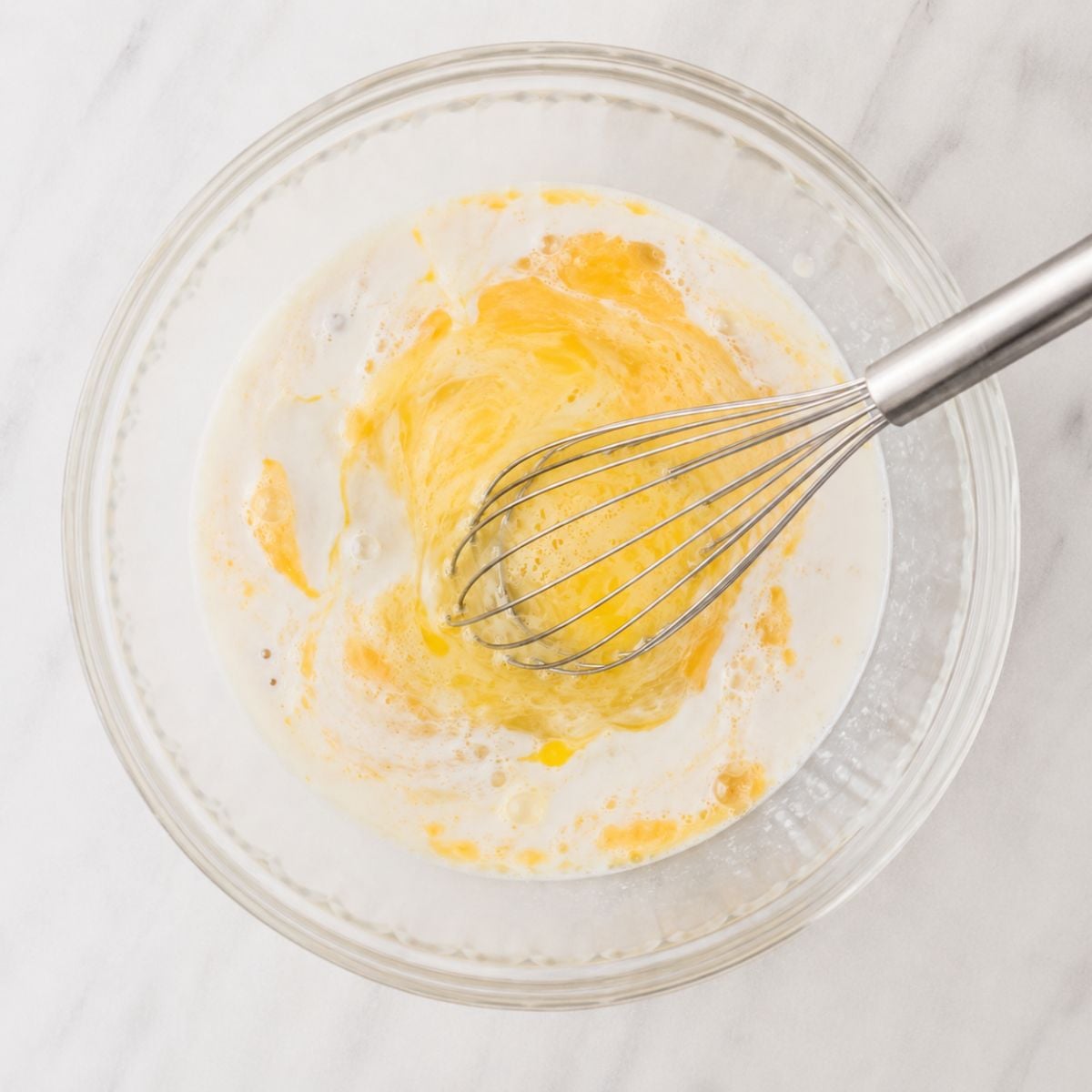 Whisked egg and milk mixture in a glass bowl for chicken egg wash