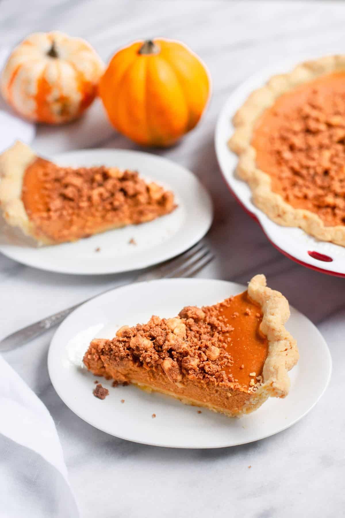 Slices of pumpkin pie with cinnamon walnut streusel on white plates