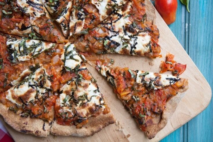 Top view of homemade pizza topped with sauce, cheese, and fresh basil.