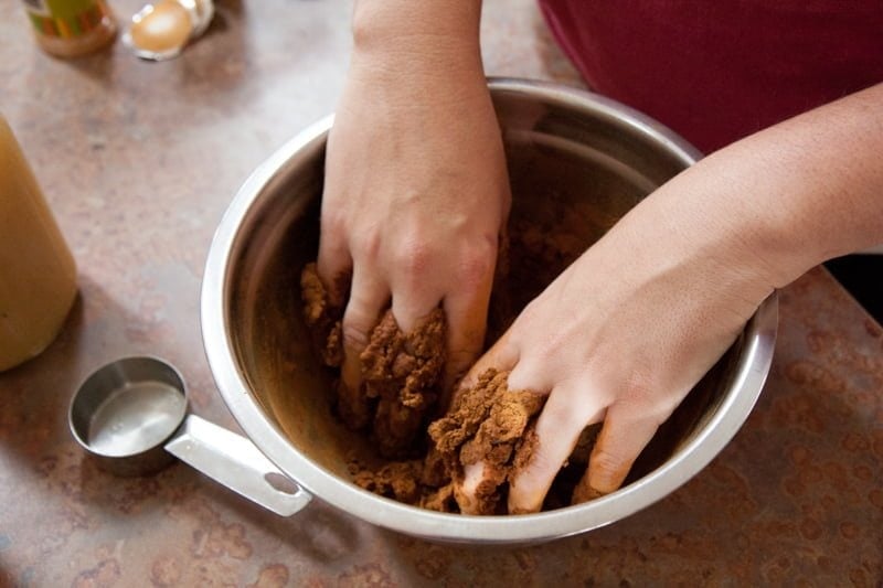 Hands mix together ornament ingredients in a mixing bowl