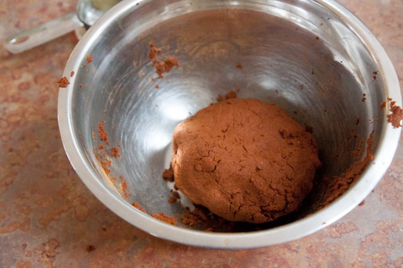 A ball of cinnamon ornament dough in a mixing bowl