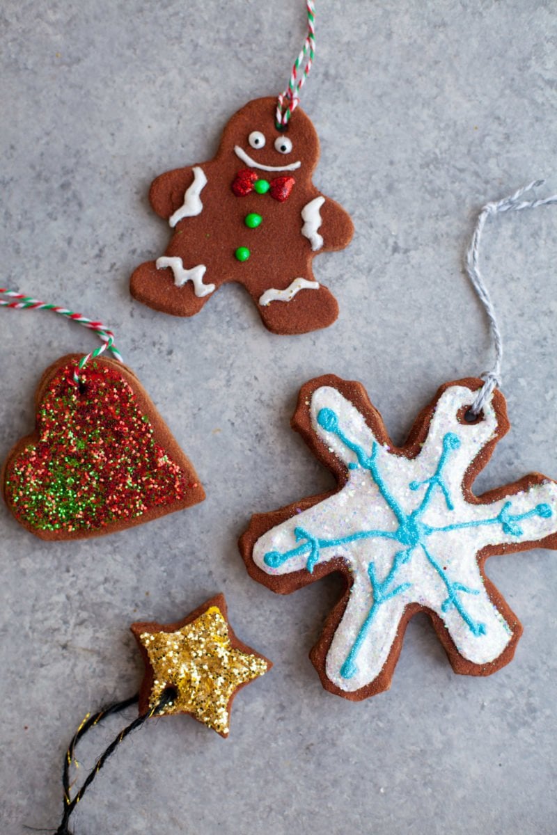 Four gingerbread ornaments that have been decorated: a gingerbread person, a heart, a snowflake, and a star