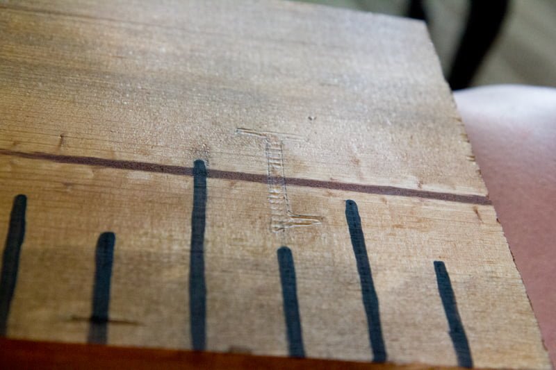 A numeral one outlined in pencil on a wooden growth chart.