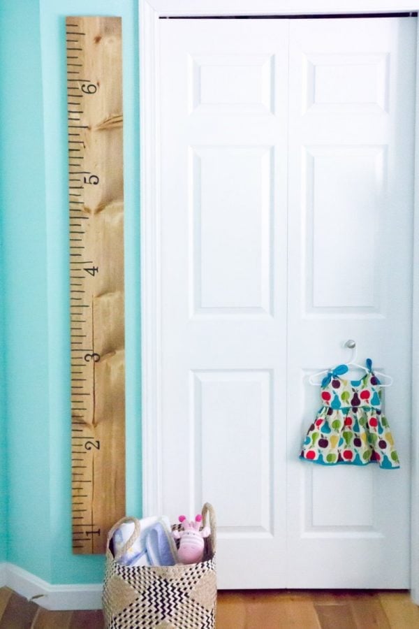 DIY Growth Chart Ruler hanging on a turquoise wall next to a white door.