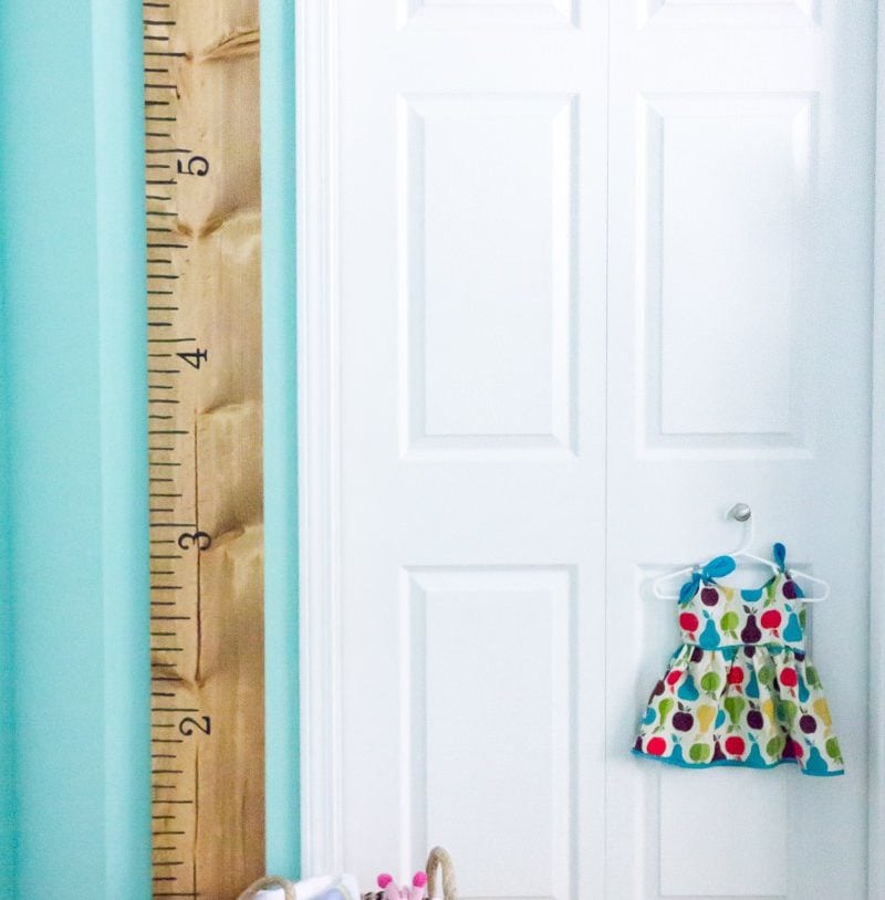 DIY Growth Chart Ruler hanging on a turquoise wall next to a white door.