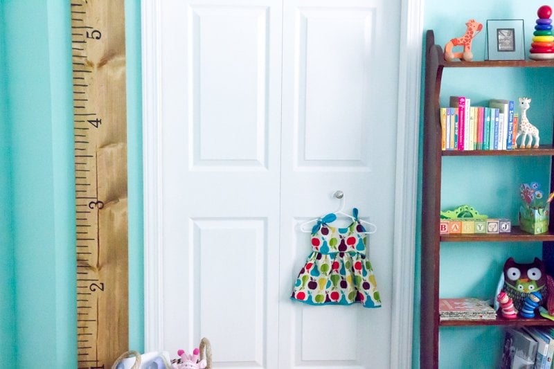 DIY Giant Growth Chart Ruler hanging on a turquoise wall next to a white door in a nursery.