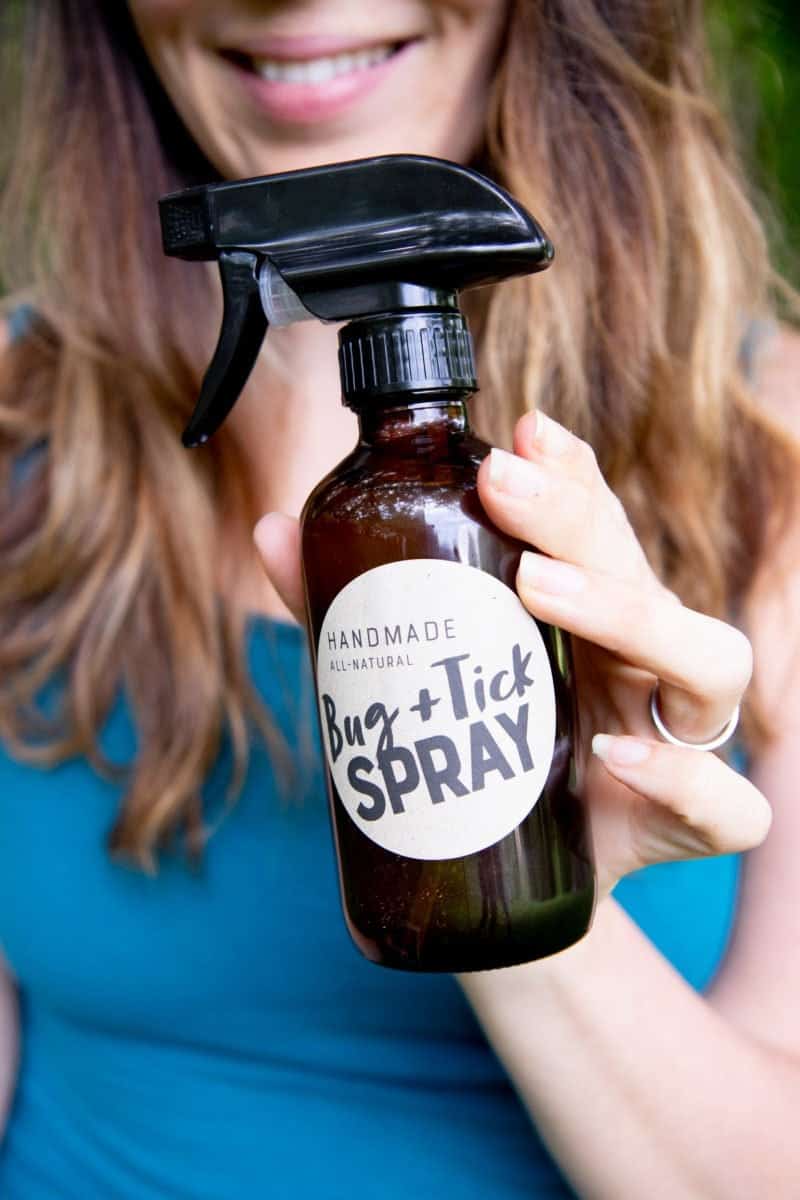 Woman holding an amber bottle of bug spray.