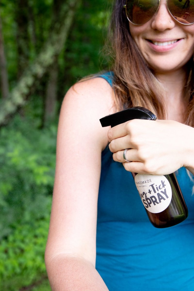 Woman spraying herself with an amber bottle of homemade all-natural tick and bug spray