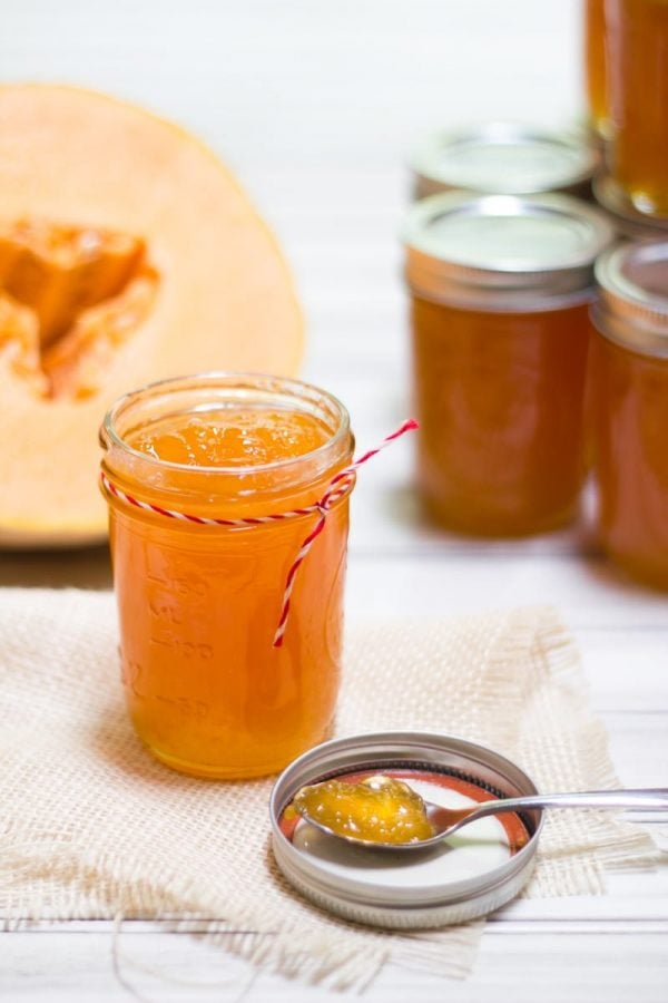 Open jar of Salted Cantaloupe Jam, with a halved cantaloupe behind