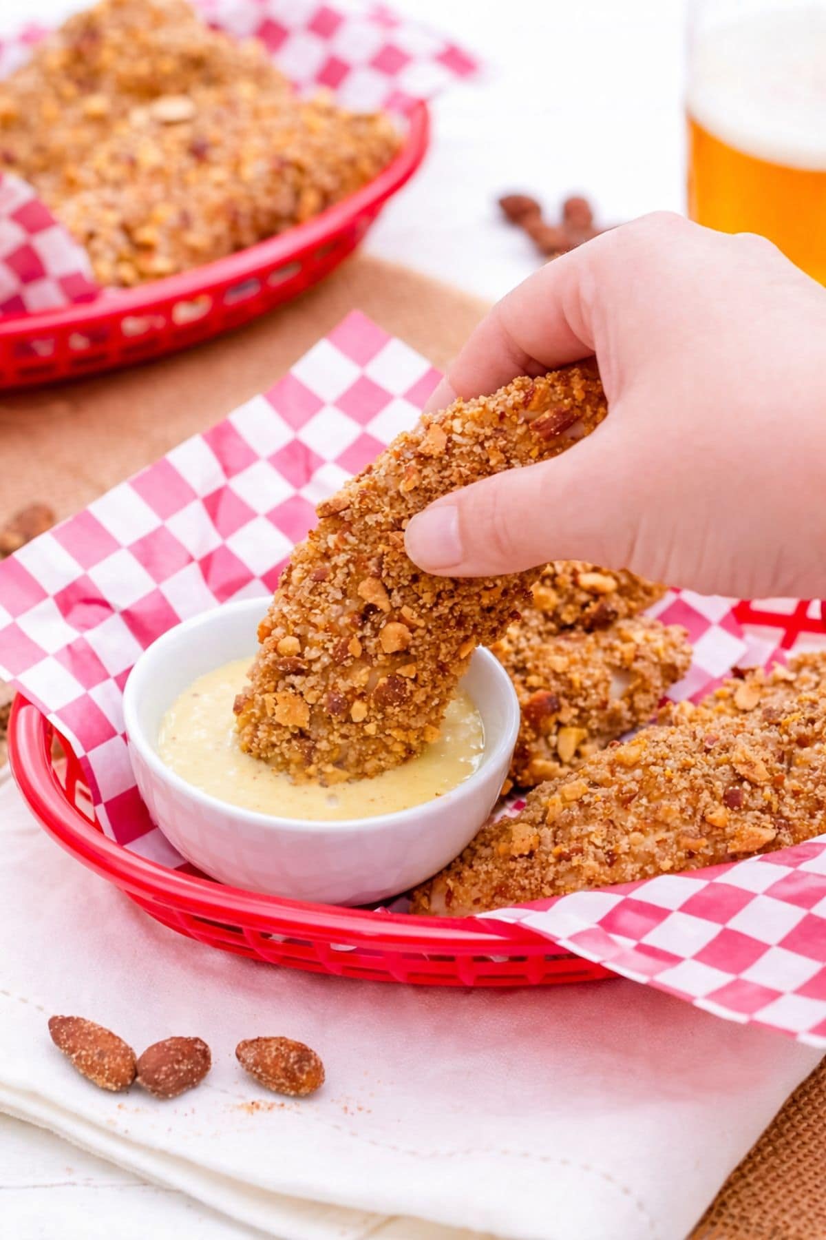 Dipping almond breaded chicken tenders into sauce
