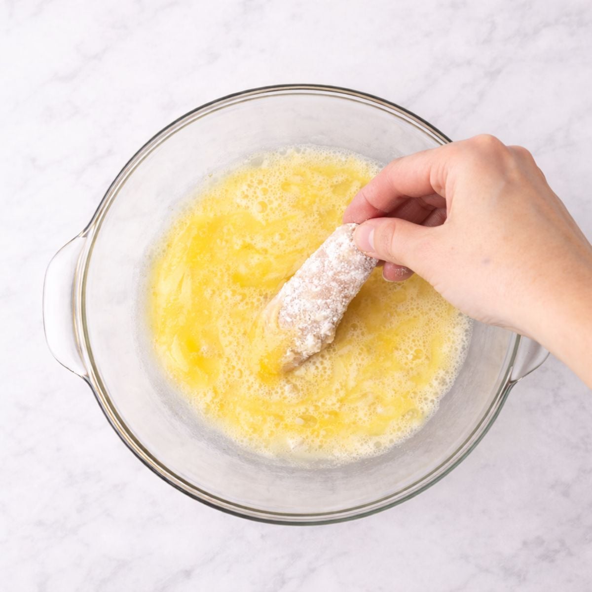 Dredging chicken strip in egg wash