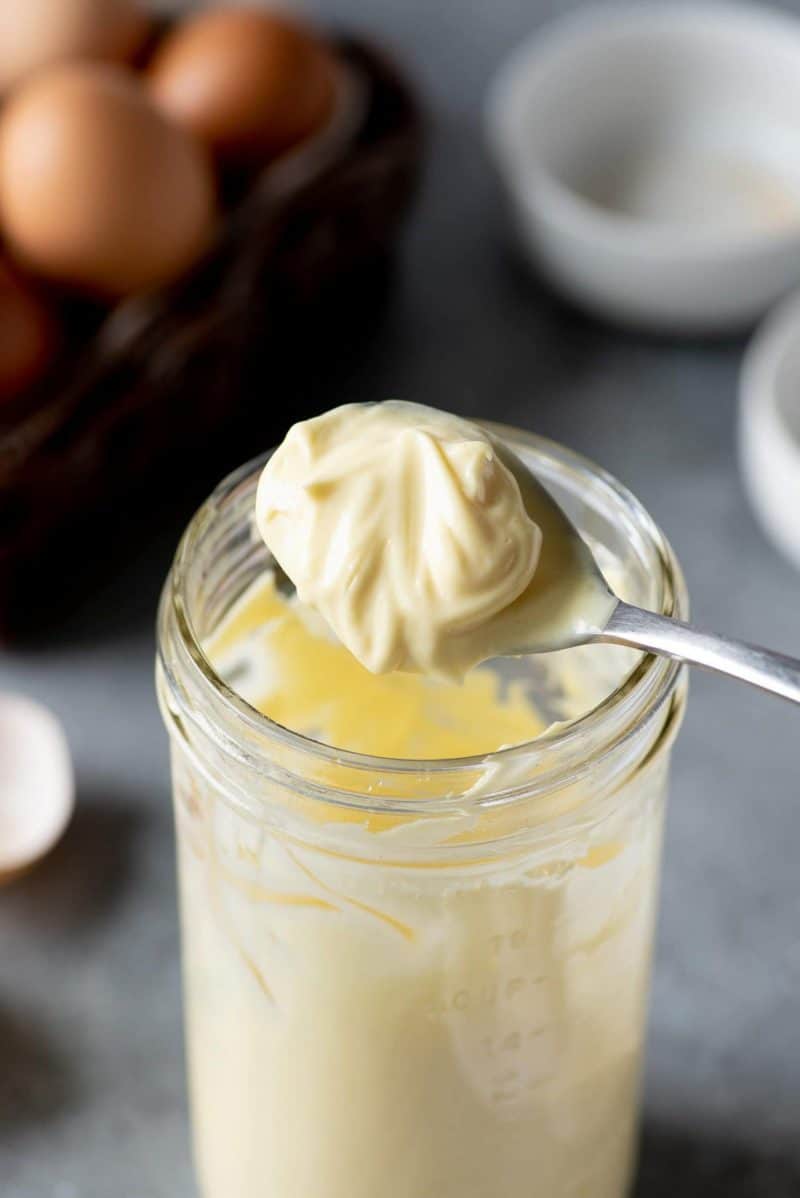 Side-angle shot of Homemade Mayo getting spooned out of a glass jar