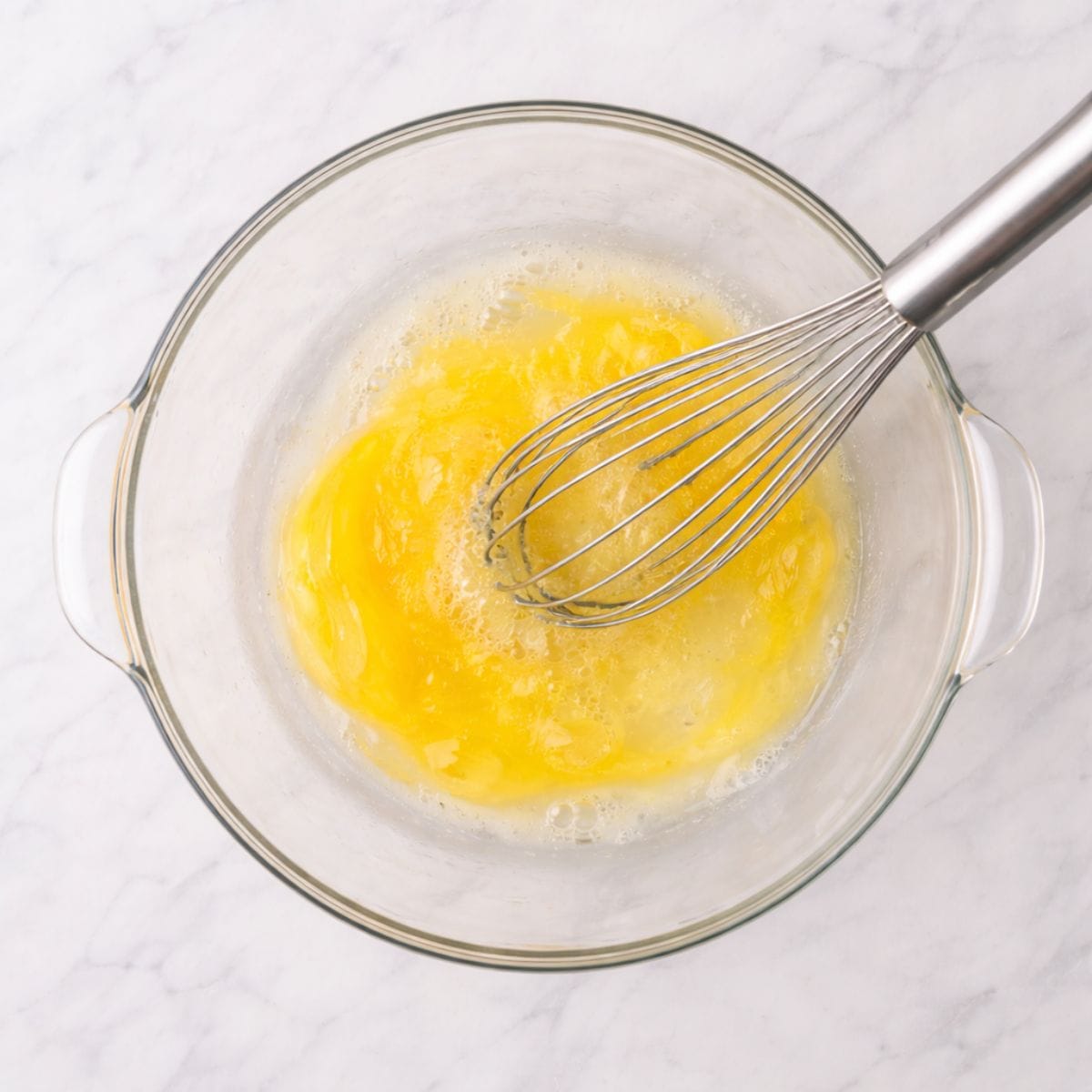 Whisking egg coating in glass bowl on countertop