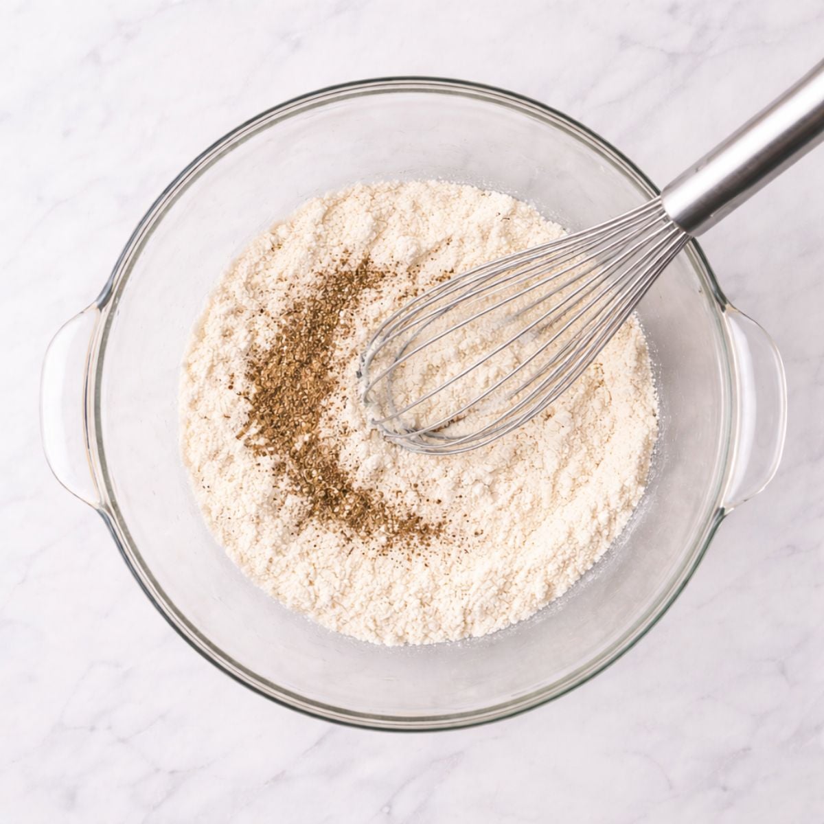 Whisking flour dredge in glass bowl on countertop