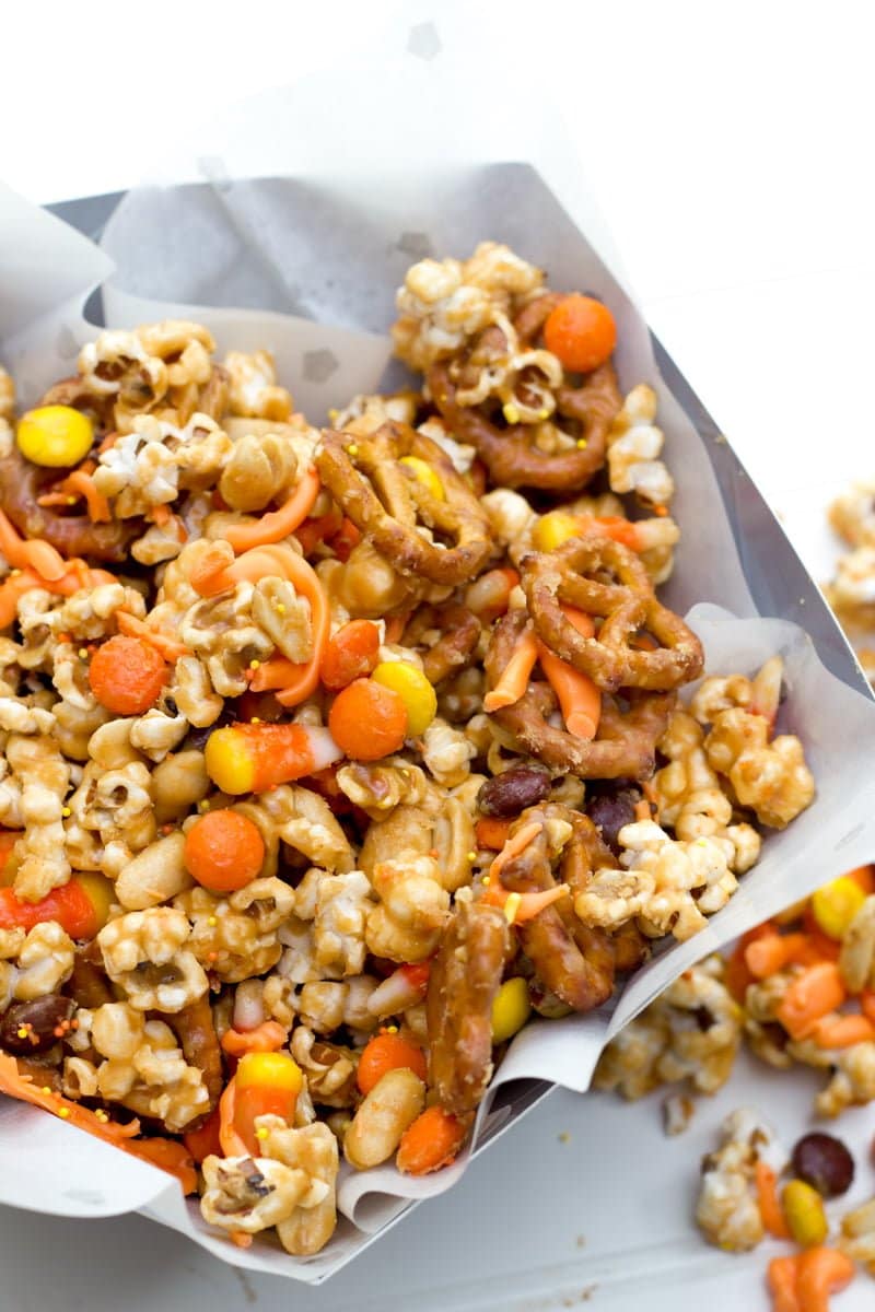 Peanut butter Halloween popcorn mix piled high in a serving container lined with parchment paper.