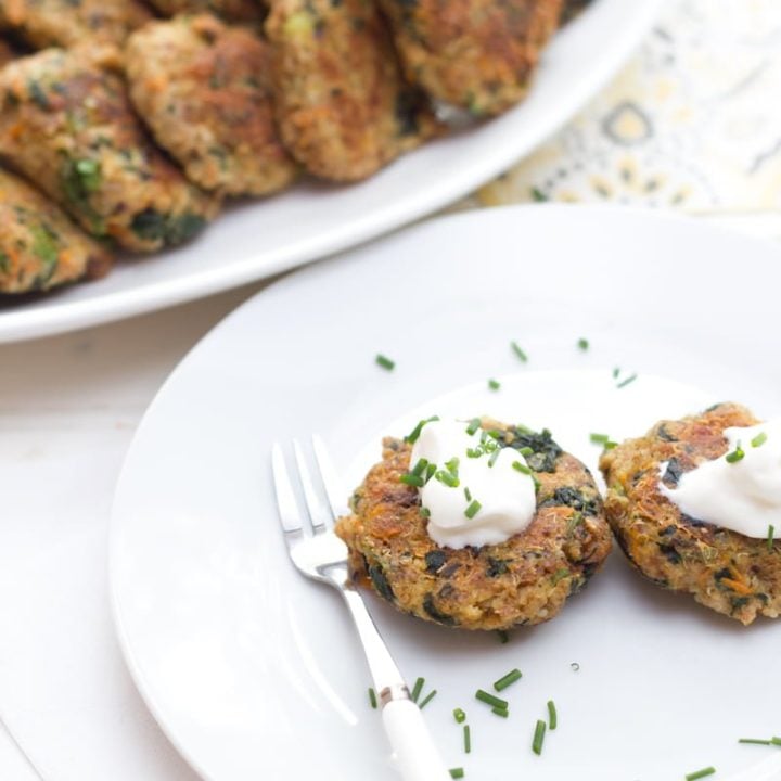 Spinach and Quinoa Patties on a white plate, topped with sour cream and chives