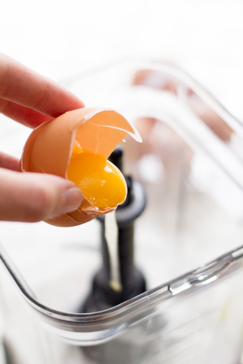 Hand cracking an egg into a blender