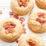 Five bourbon and brown sugar cookies topped with bacon pieces on a white background.