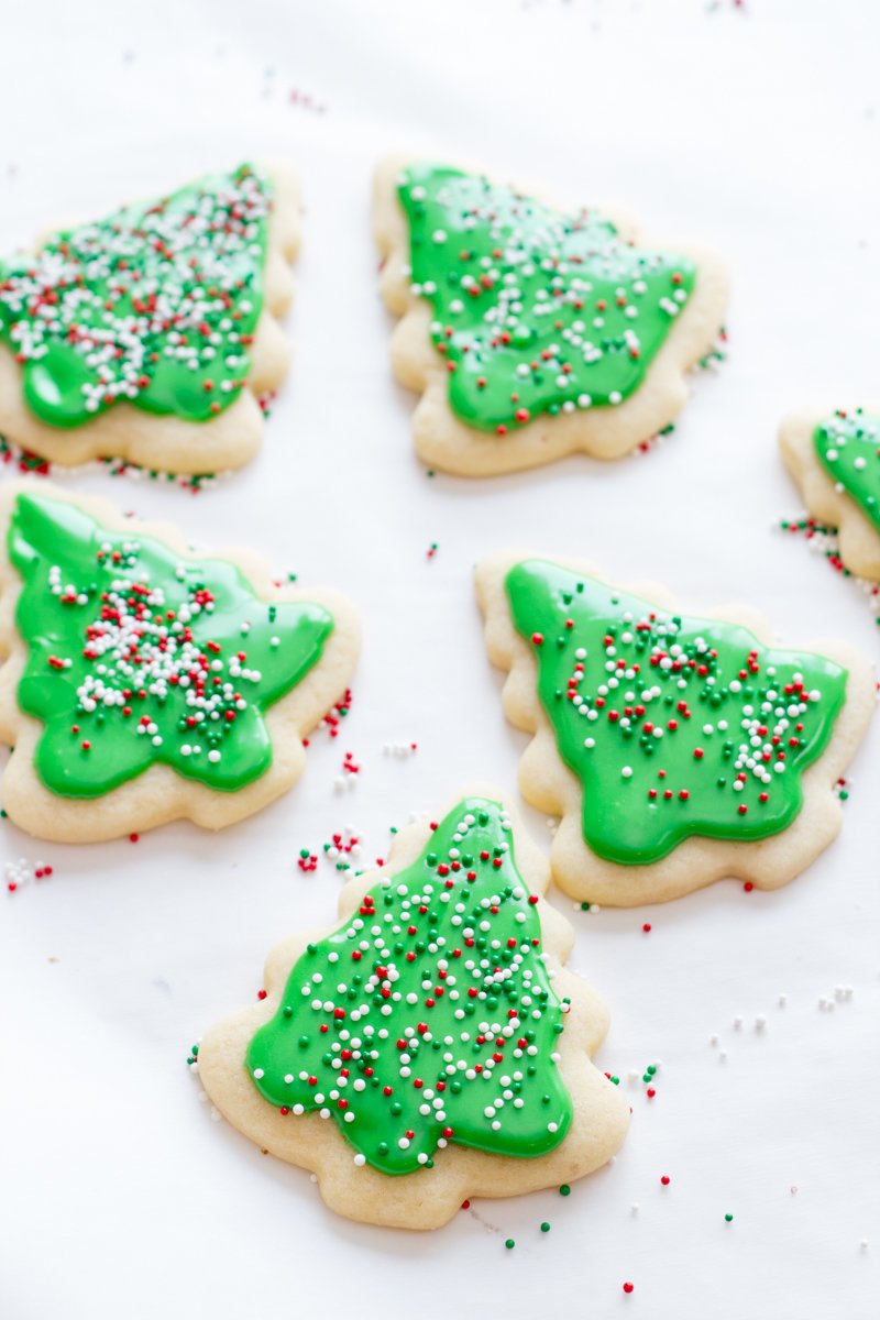 Decorated Christmas tree sugar cookies with green frosting rest on a white background.