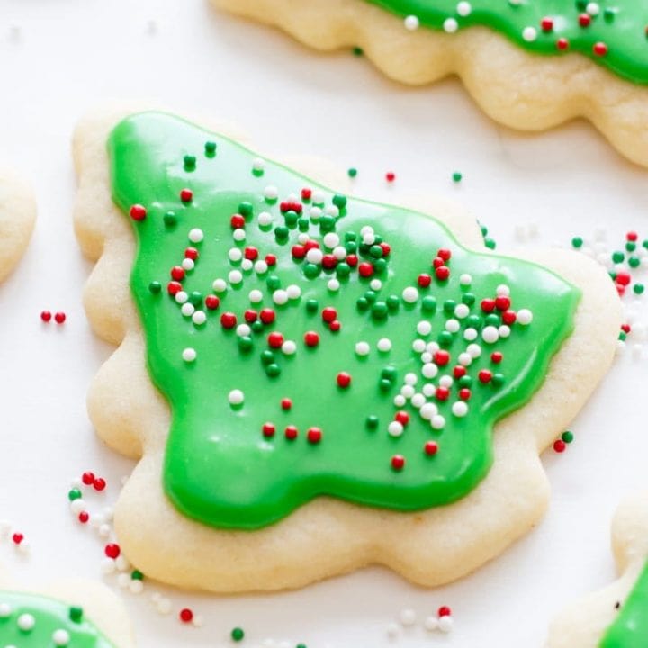 Closeup view of a cut out sugar cookie shaped like a christmas tree topped with green icing and sprinkles.