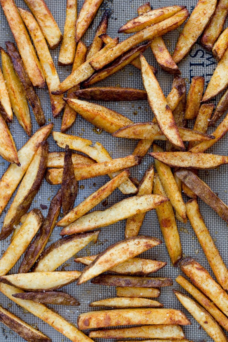 Overhead of oven baked fries on a baking sheet lined with a silicone mat.