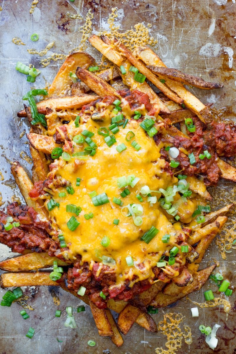 Close-up of homemade chili cheese fries on a baking sheet garnished with green onion.