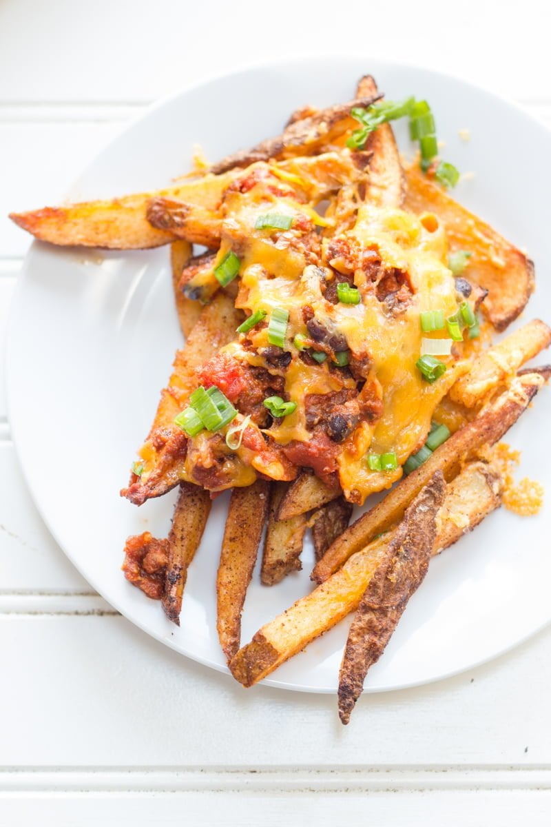 A serving of homemade chili cheese fries on a white plate.