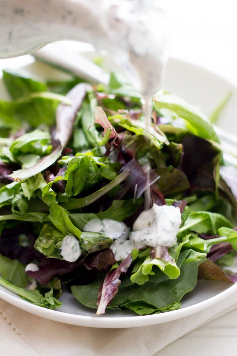 Close up of a bowl of salad with ranch dressing in a white bowl.