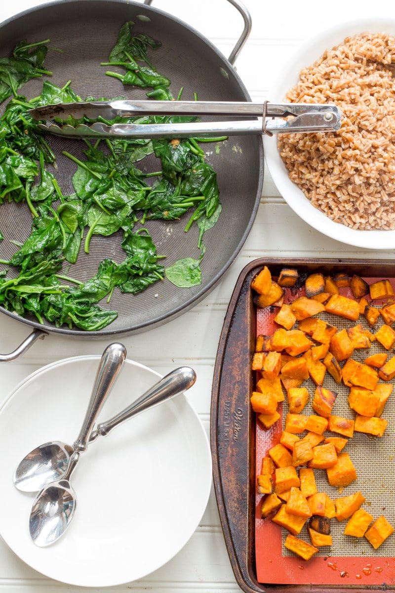 Components for Curried Sweet Potato Breakfast Bowls in individual pans - curried sweet potatoes, sauteed greens, and cooked farro