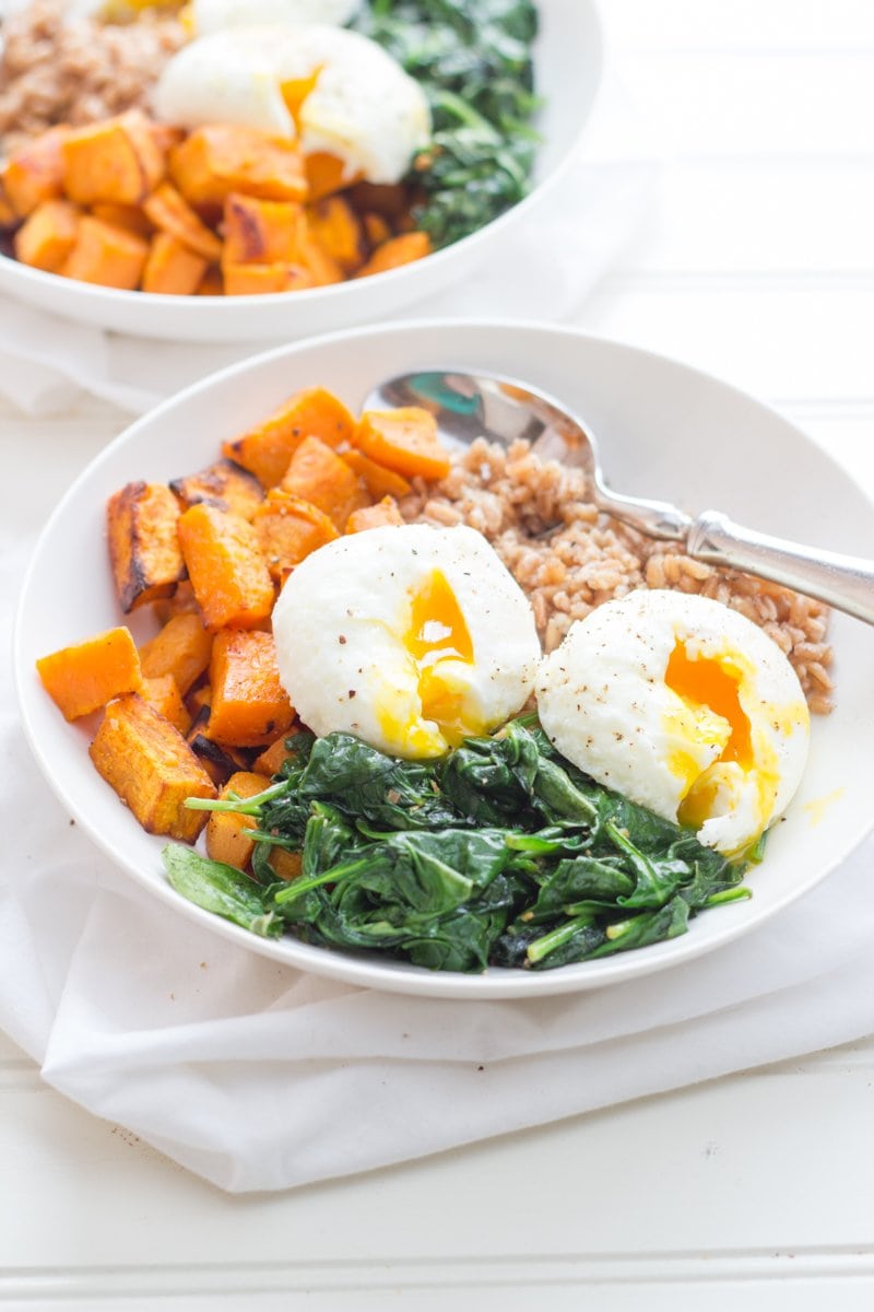 Curried Sweet Potato Breakfast Bowls in white bowls - cooked farro, roasted sweet potatoes, sauteed greens, and poached eggs
