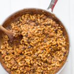 A pot of taco pasta skillet with a wooden spoon stirring it.