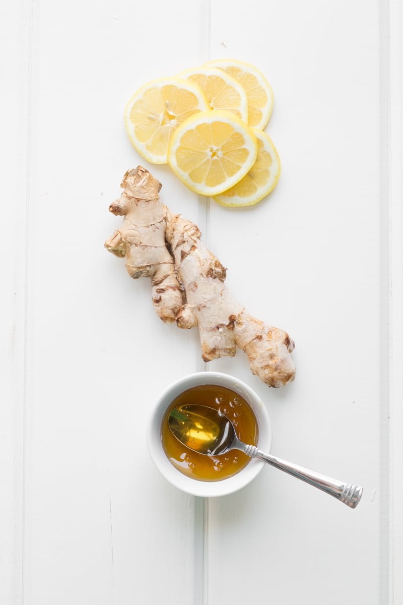 Ingredients for lemonade sit together - ginger, honey and lemons.