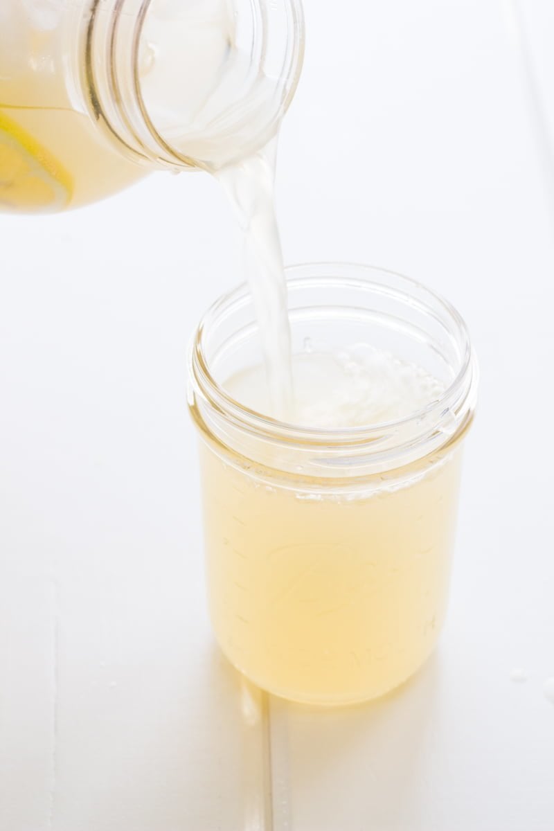 A jar pours Honey Ginger Lemonade into a mason glass.
