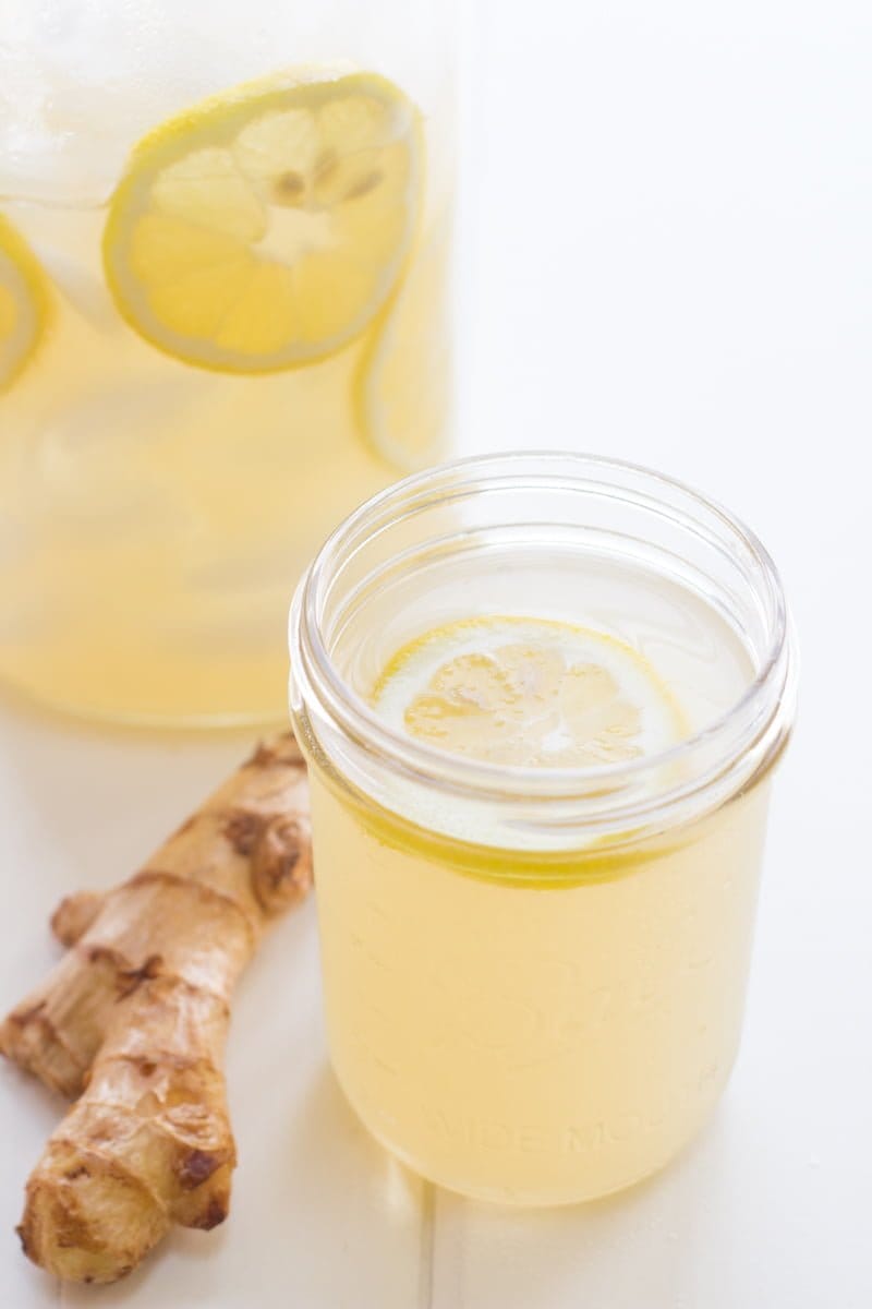 A glass of Honey Ginger Lemonade sits next to ginger.