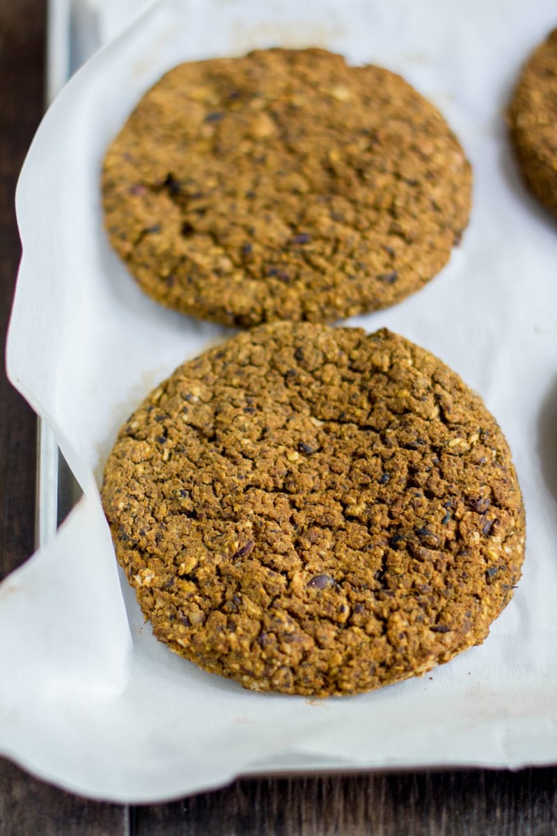 Formed patties for pumpkin black bean burgers sit on parchment paper, ready to be cooked.