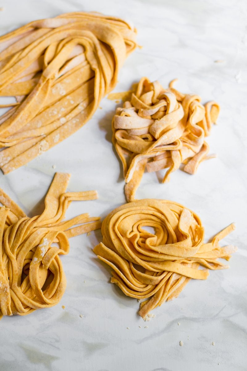 Top view of pumpkin pasta strands cut and formed into individual serving bundles.