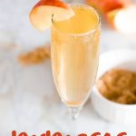 Apple Cider Mimosa garnished with an apple slice. Text overlay reads "Apple Cider Mimosas."