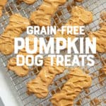 Dog treats shaped like bones and drizzled with a peanut butter glaze are on a wire cooling rack. A text overlay reads "Grain-Free Pumpkin Dog Treats."