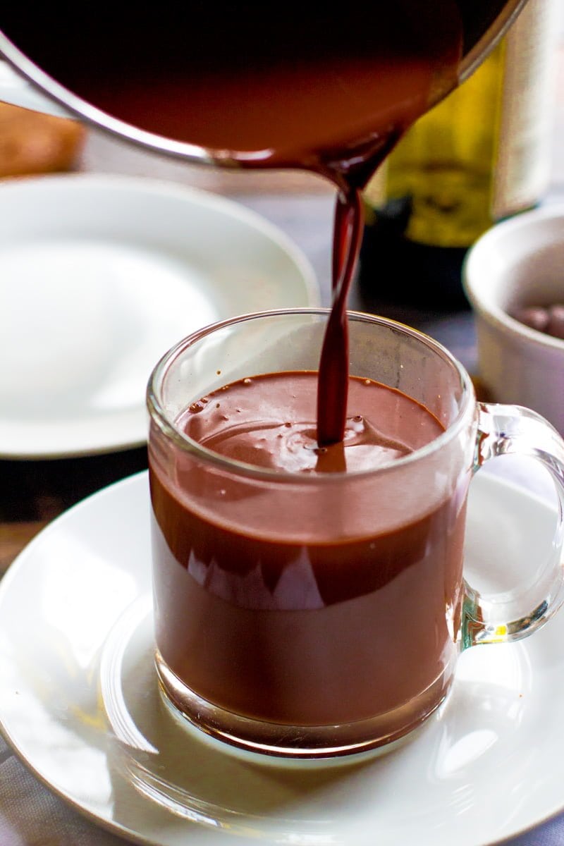 Red Wine Hot Chocolate being poured from a pot into a clear glass mug